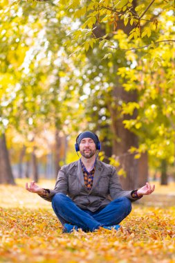 Dijital detoks - orta yaşlı serbest çalışan ofis ve şehir gürültüsünden dinleniyor. Sonbahar şehir parkında meditasyon yapıyor..
