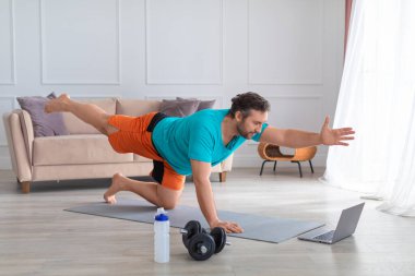 Evde pilates yaparken orta yaşlı bir adam. Denge egzersizi. Sağlıklı yaşam tarzı kavramı.