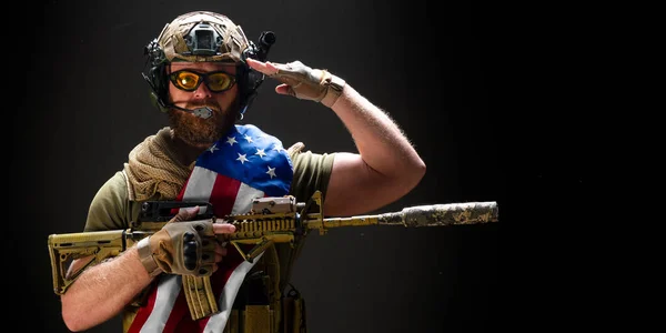 Un soldado americano sostiene una bandera en su hombro y saluda. Concepto del Día del Recuerdo de los Veteranos. — Foto de Stock