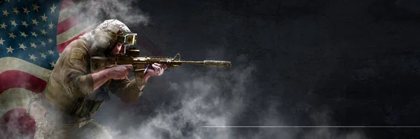 Combatiente profesional de fuerzas especiales, durante una operación especial está envuelto, en humo contra una pared de hormigón oscuro y fondo de la bandera de Estados Unidos - él está defendiendo la bandera. Formato de foto 3x1. — Foto de Stock