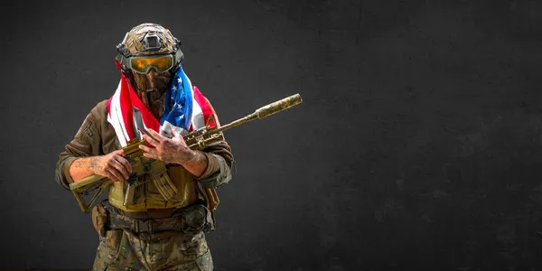 American soldier stands against the background of a concrete wall with a flag on his shoulders. Concept of the day of remembrance of veterans. Photo format 2x1. — Stock Photo, Image