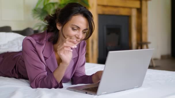 Medelålders kvinna framför en laptop monitor i sängen. Frilans - hon har online videosamtal och aktivt gester. — Stockvideo
