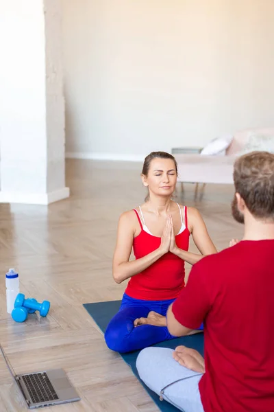 İnternette yoga dersi veren bir çift evde meditasyon yapıyor. Dikey fotoğraf. — Stok fotoğraf