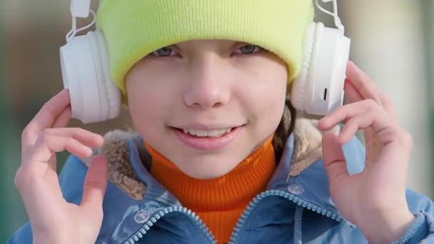 Tiener meisje luisteren naar de muziek via draadloze hoofdtelefoon en online smartphone app outdoor. — Stockvideo