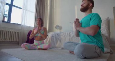 Ev içinde meditasyon yapan yaşlı bir çiftin fotoğrafı. Akıl sağlığı konsepti. Yoga pratiği. 4K görüntü.