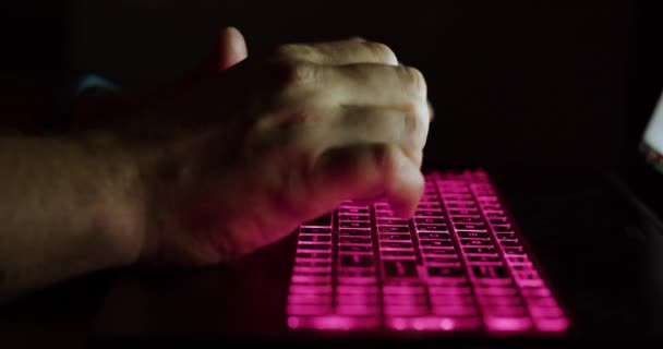 Las manos masculinas de cerca están escribiendo texto en el teclado del portátil por la noche. — Vídeo de stock
