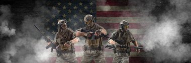 Üç profesyonel özel kuvvet askeri, koyu beton bir duvar ve Amerikan bayrağı arka planına karşı yürütülen özel bir operasyon sırasında. Bayrağı savunuyorlar. Fotoğraf biçimi 3x1.