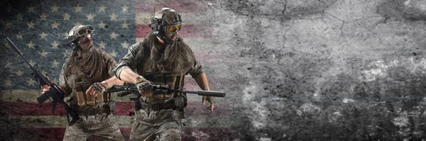 Dos soldados mercenarios caminan después de la finalización exitosa de la operación contra el fondo de un muro de hormigón con una bandera estadounidense. Formato 3x1. Collage - un modelo, en dos poses. — Foto de Stock