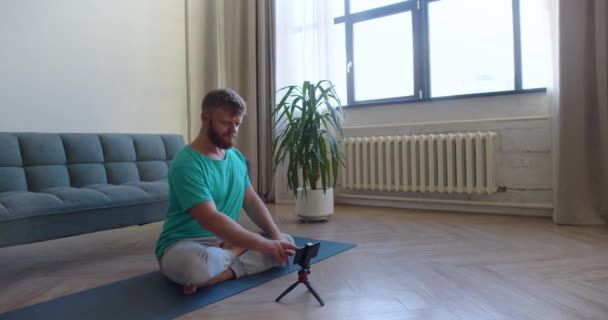 Orta yaşlı bir adamın evde yoga yapmak için internetten egzersiz rehberi seçerken ki görüntüsü. — Stok video