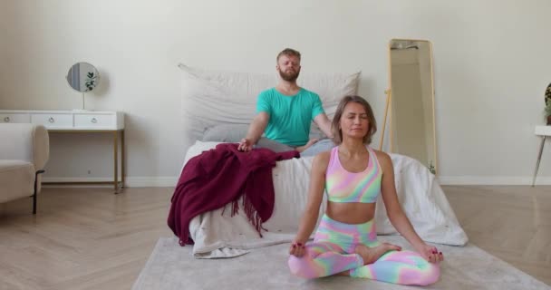 Orta yaşlı bir çiftin evdeki yatakta meditasyon yaparken 4K görüntüsü.. — Stok video