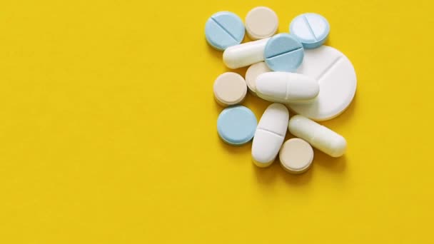 Vista de cerca, rotación - pastillas y cápsulas sobre un fondo amarillo. — Vídeo de stock