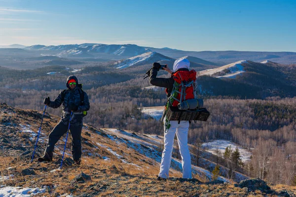 Couple d'âge moyen faire de la randonnée dans les montagnes alpines d'hiver à l'aube - ils font une photo avec smartphone. — Photo