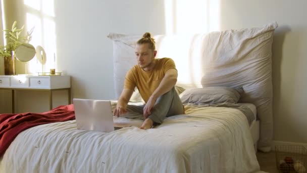 Egy fiatalember kiválaszt egy online jóga útmutatót, lótuszpozícióban ül és meditálni kezd.. — Stock videók