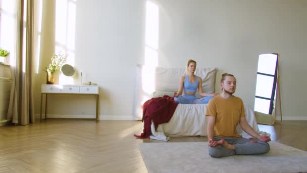 Filmaufnahmen eines jungen Paares, das im häuslichen Innenraum meditiert. Yoga-Praxis. 4K-Filmmaterial. — Stockvideo