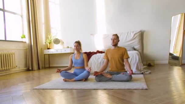 4k beelden van een jong koppel mediteren thuis samen. — Stockvideo