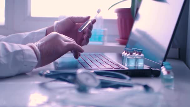 연구소 의사는 사무실에서 일하고 있다 - 그는 노트북의 최신 백신에 대한 보고서를 작성하고 있다. — 비디오