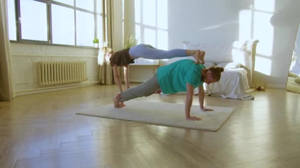 Jong paar oefenen acro-yoga thuis op de vloer. — Stockvideo