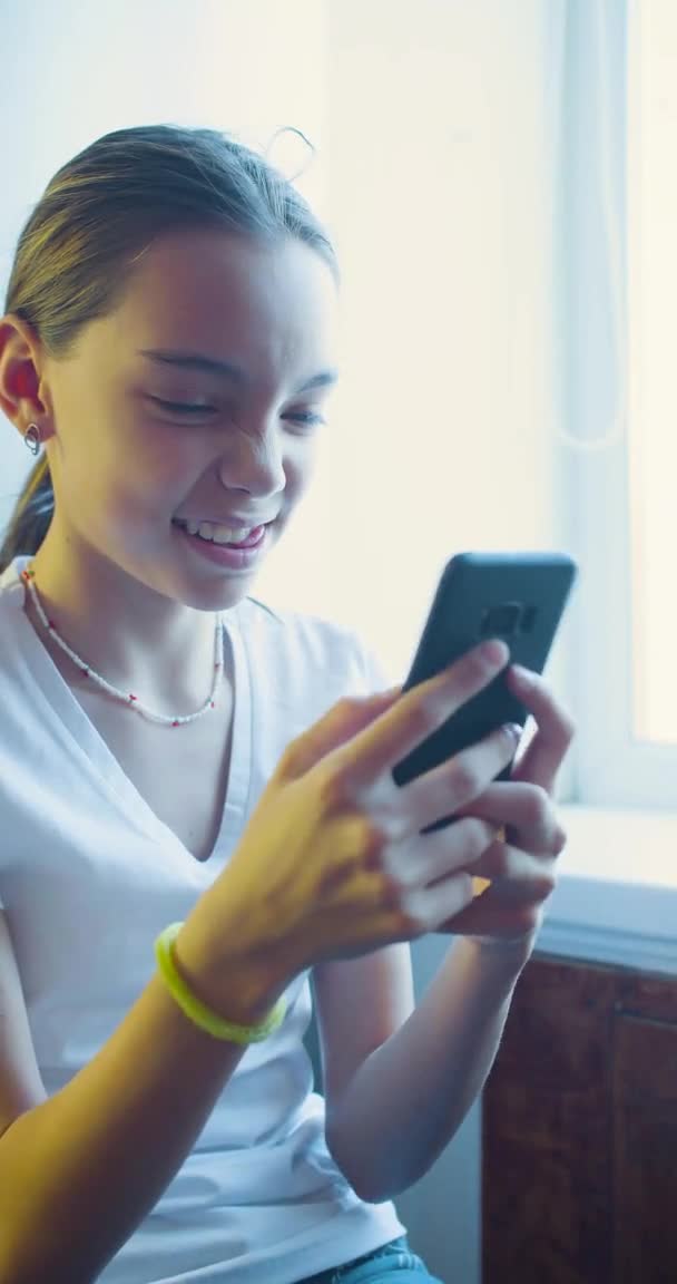 Chica adolescente jugando al videojuego tocando la pantalla del teléfono inteligente - ella se divierte en casa. — Vídeos de Stock