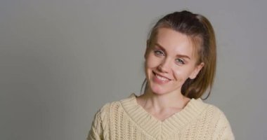 Smiley woman make a photo with smartphone over grey background.