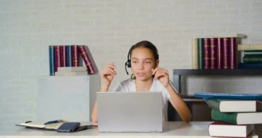 Teenage girl during an online conversation in front of a laptop monitor. She talks, smiles and gestures.