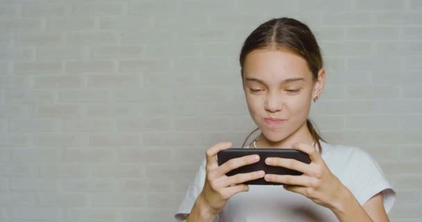 Adolescente chica divirtiéndose mientras juega video juego tocando la pantalla del teléfono inteligente. — Vídeos de Stock