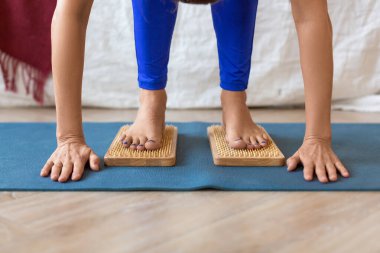 A woman standing on a board with sharp nails - feet and legs close-up. Sadhus boards yoga practice.
