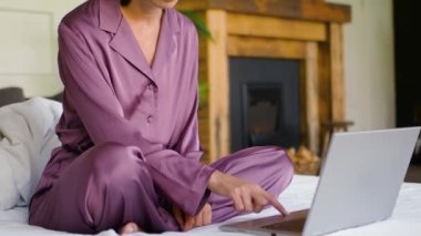 Cropped view of a woman chooses a tutorial on the Internet and practices yoga at home in front of a laptop monitor.