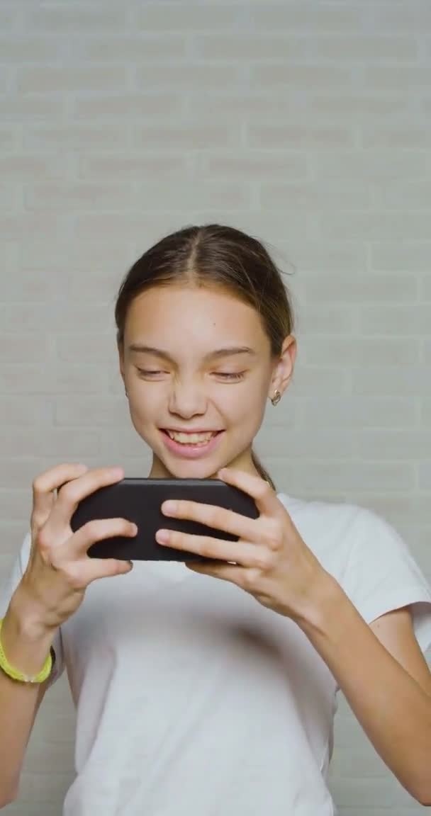 Vertical video of a teenager girl having fun while playing video game touching smartphone screen. — Αρχείο Βίντεο