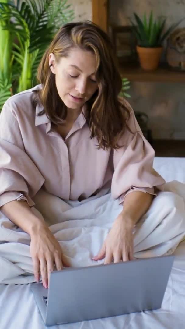 35 år gammal kvinna framför en laptop bildskärm i sängen. Frilans - hon talar över videokommunikation och aktivt gester. — Stockvideo