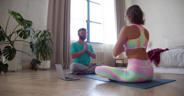 Couple meditating at home with online yoga tutorial. 4K footage. — Vídeo de stock