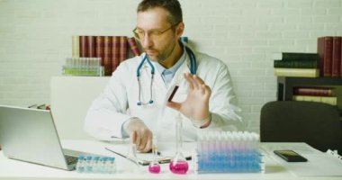 Doktorun yavaş çekimde çekilmiş resmi laboratuvarda rapor yazıyor. Modern aşıların geliştirilmesi üzerine araştırma.