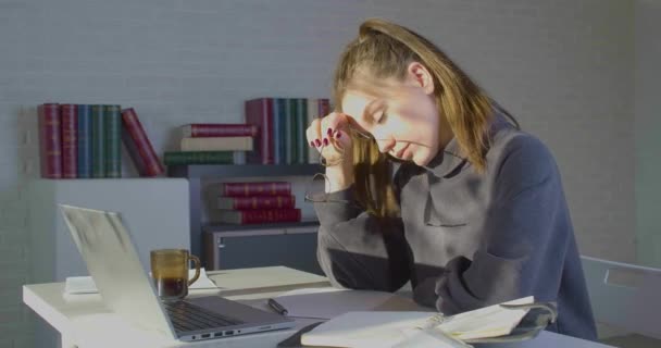 Müde nach langer Nutzung des Computers junge Frau nimmt ihre Brille ab Reiben Nasenbrücke reduziert schmerzhafte Gefühle Ruhe am Arbeitsplatz sitzen. — Stockvideo