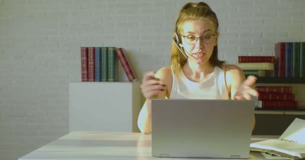 Junge erwachsene Frau arbeitet im Büro vor einem Laptop-Monitor - sie hat ein Online-Videotelefonat. Frontansicht. — Stockvideo