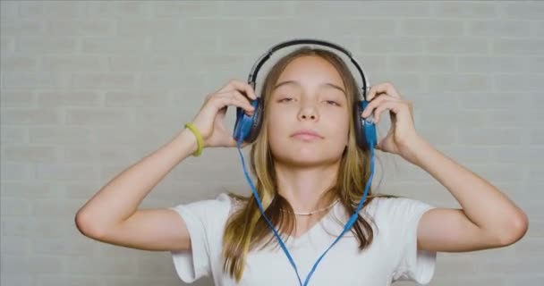 Tiener meisje draagt een koptelefoon en luistert naar de hardrock muziek. — Stockvideo