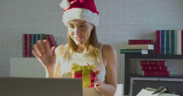 Giovane donna in ufficio la vigilia di Natale a Santa Hat. Ha ricevuto un regalo e ringrazia il suo ragazzo durante una videochiamata online. — Video Stock