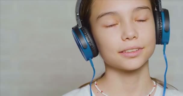 Close-up beelden van een tienermeisje in een blauwe koptelefoon luisterend naar de kalme muziek. — Stockvideo