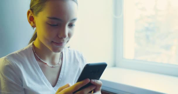 Adolescente chica jugando videojuego con su teléfono inteligente - ella se divierte en casa. — Vídeos de Stock