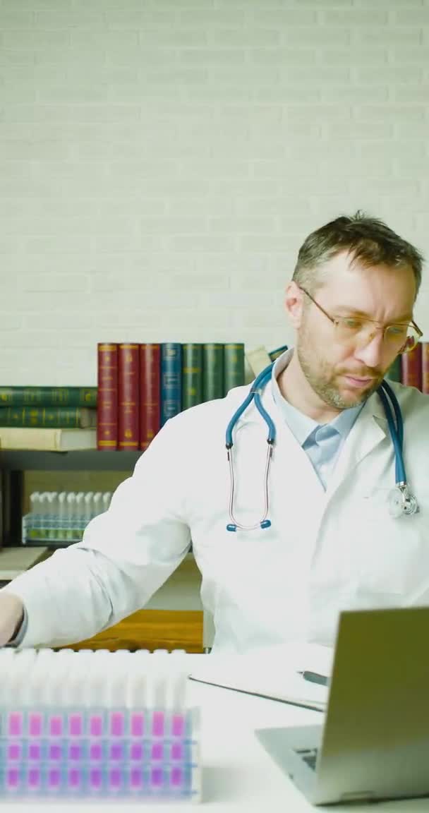 Vertikale Aufnahmen eines Arztes, der in seinem Büro einen Bericht schreibt. Forschung zur Entwicklung moderner Impfstoffe. — Stockvideo
