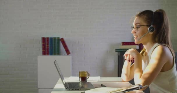 Young adult woman works in front of a laptop monitor in the office - she having online video call. — Stock Video