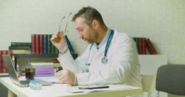 İşteyken doktor gözlüğünü çıkarıp burnunun köprüsünü ovuyor. Çok yorgun..