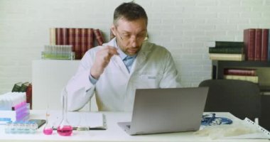 Bir doktorun ön görüntüsü ofisinde bir rapor yazar. Modern aşıların geliştirilmesi üzerine araştırma.
