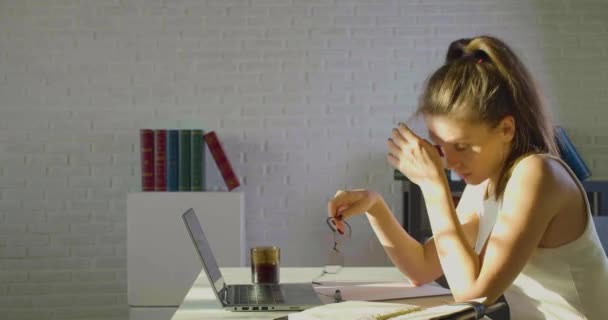 Deadline concept - moe na langdurig gebruik van computer jonge vrouw doet haar bril af wrijven neus brug vermindert pijnlijke gevoelens rust zitten op het werk. — Stockvideo