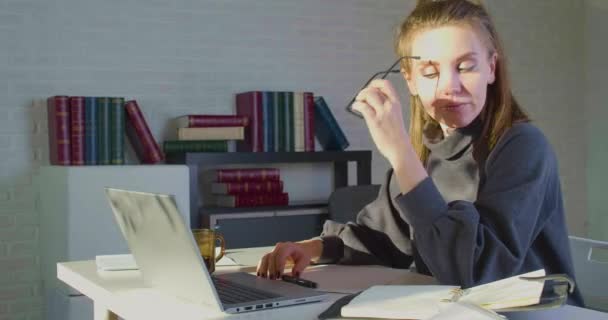 Усталость после длительного использования компьютера молодая женщина снимает очки потереть нос мост уменьшает болезненные чувства отдыха сидеть на рабочем месте. Концепция срока действия. — стоковое видео