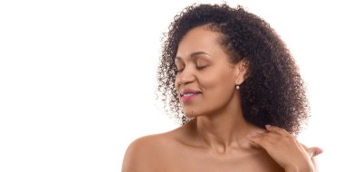 35 yaşında, beyaz arka planda soyutlanmış, gözleri kapalı, pürüzsüz tenine dokunan Afro-Amerikan bir kadın. Biçim fotoğrafı 2x1.