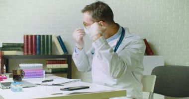 Doktor iş gününün sonunda maskesini ve eldivenlerini çıkardı. Çok yorgundu..