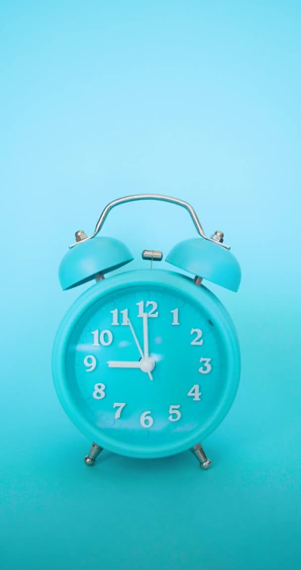 Vertical video with sound - a blue alarm clock on a blue background rings at 9 AM — Stock Video