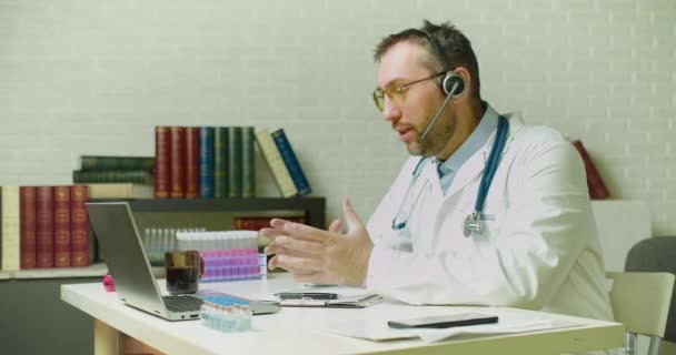 A doctor is talking to a colleague via video link about the latest research - he is drinking coffee during an online video call. — Stock Video
