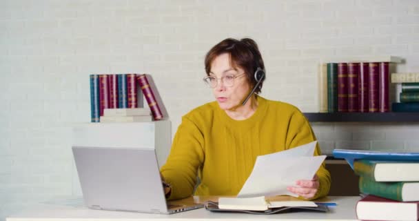 Αργή κίνηση μιας ηλικιωμένης γυναίκας που εργάζεται μπροστά από ένα φορητό υπολογιστή οθόνη στο γραφείο το βράδυ. — Αρχείο Βίντεο