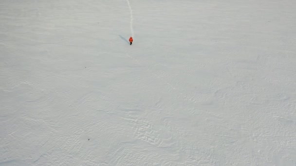 Luchtfoto 4k beelden - een man met een rugzak en stokken loopt door de besneeuwde woestijn laat een keten van voetafdrukken achter. — Stockvideo