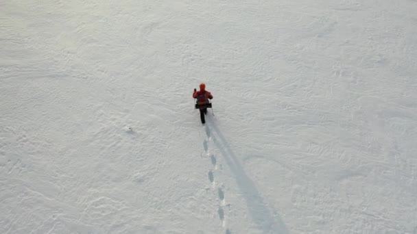 Images 4k, vue depuis drone - un voyageur seul avec un sac à dos marche à travers le désert enneigé. — Video